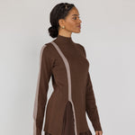 Woman wearing a brown long-sleeve top with a truffle stripe on a plain background