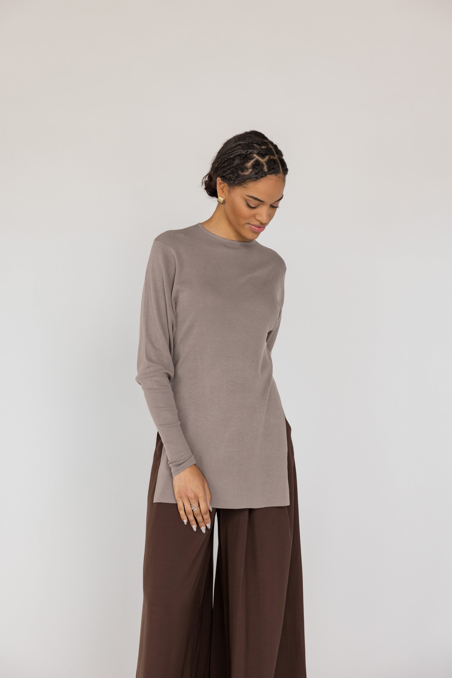 Woman wearing a brown long-sleeve top and wide-leg pants on a white background