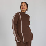 Woman wearing a brown outfit with truffle stripes on a plain background