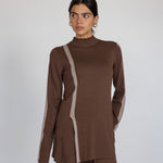 Woman wearing a brown outfit with truffle stripe against a plain background