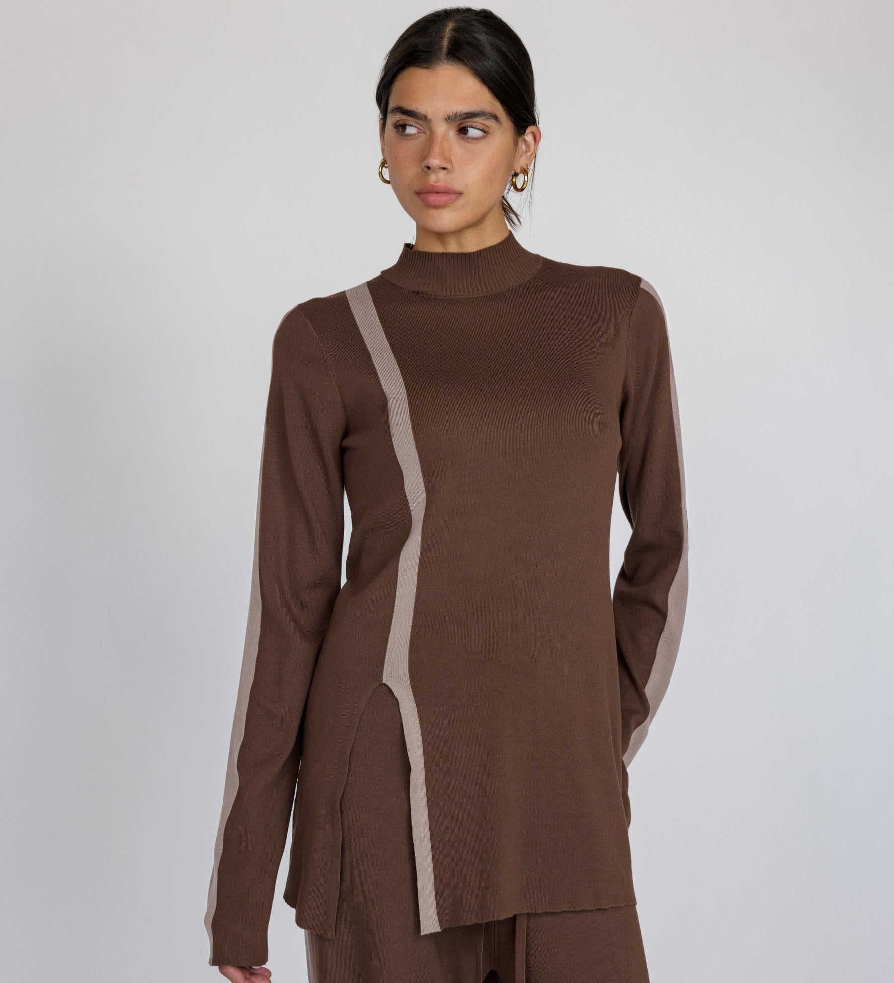 Woman wearing a brown outfit with truffle stripe against a plain background