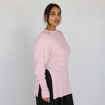 Woman wearing a light pink sweater against a plain background