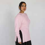 Woman wearing a light pink sweater against a plain background