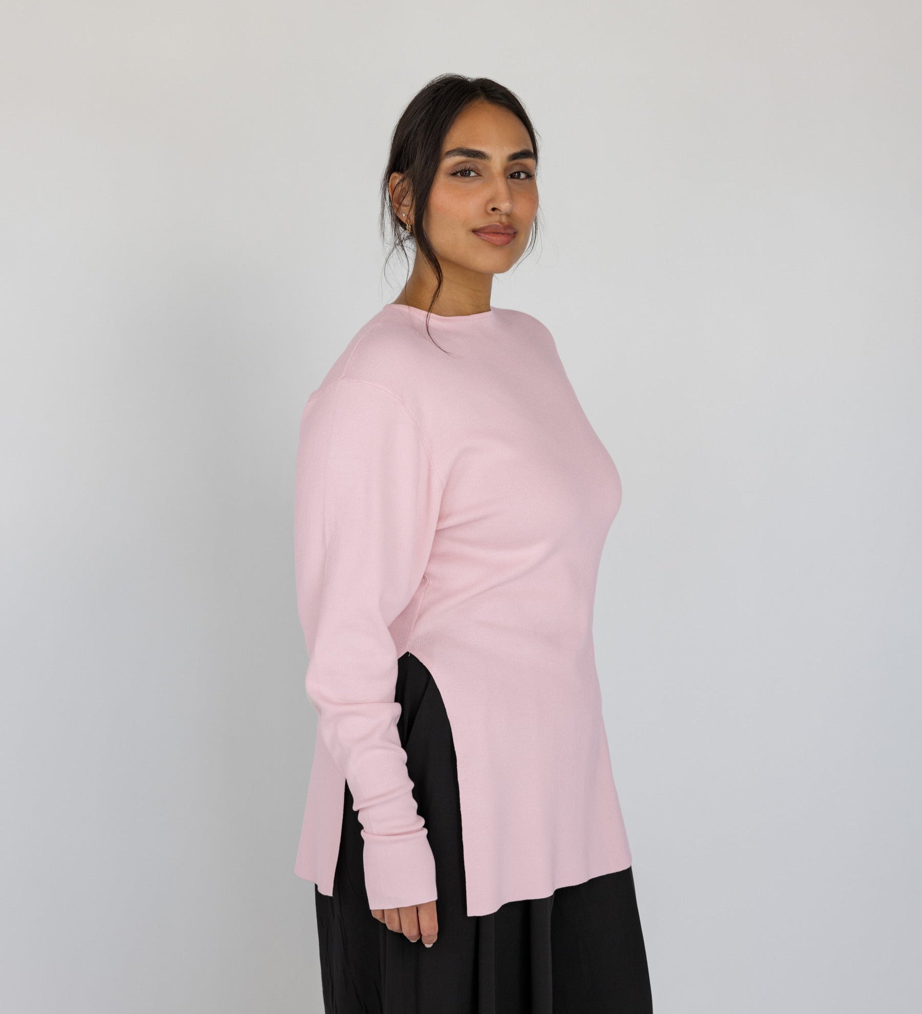 Woman wearing a light pink sweater against a plain background