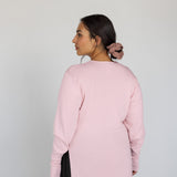 Person wearing a light pink knit top against a white background