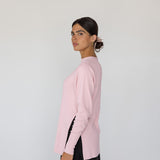 Woman wearing a pink sweater and black pants on a white background