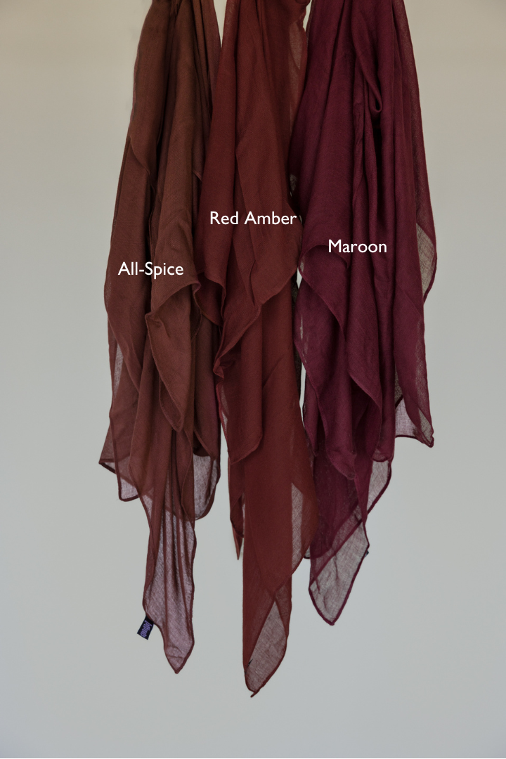 Maroon hijab hanging next to other shades for a side-by-side comparison of color depth and tone.