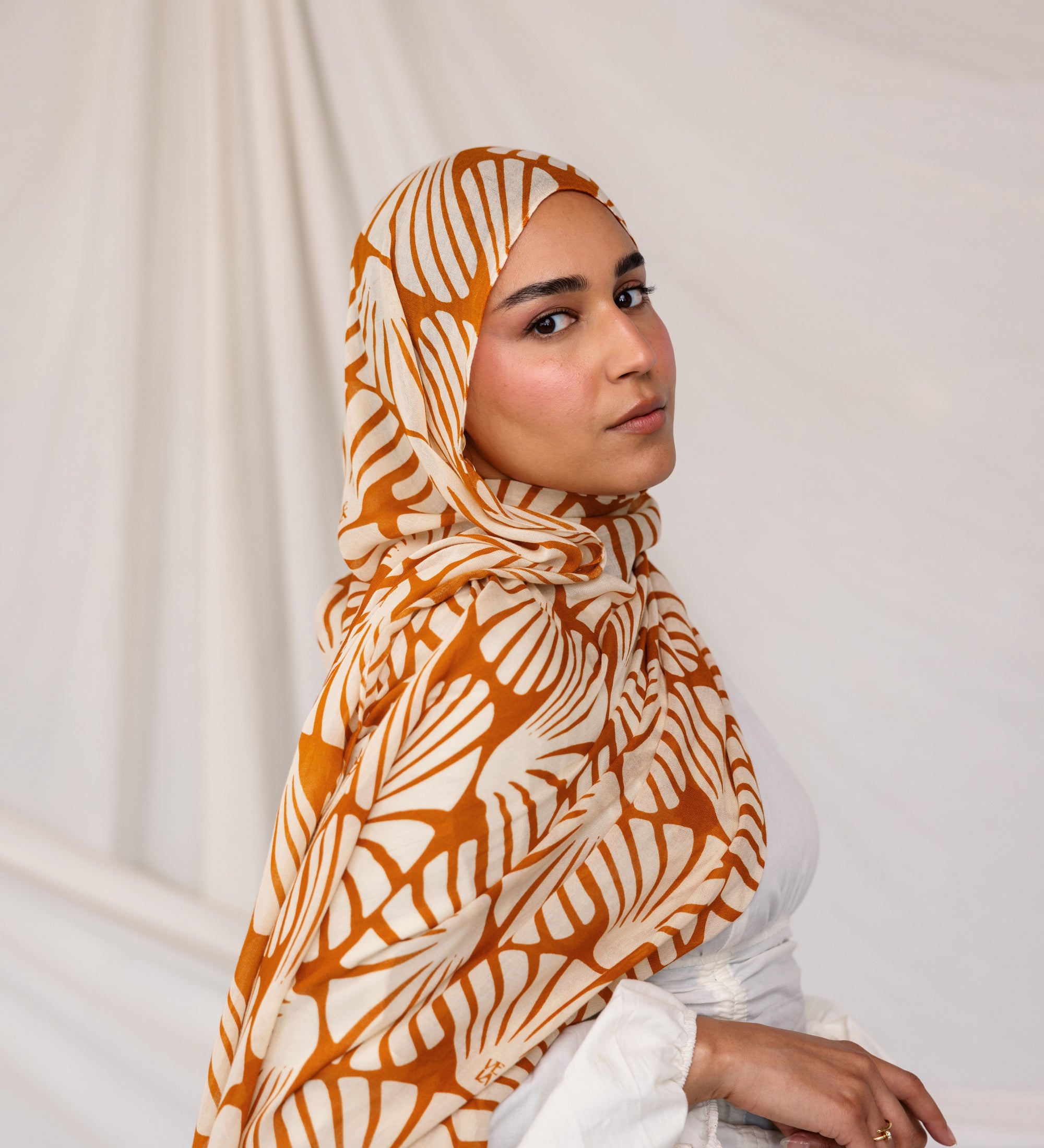 Woman wearing Amber Shells printed hijab against a plain background