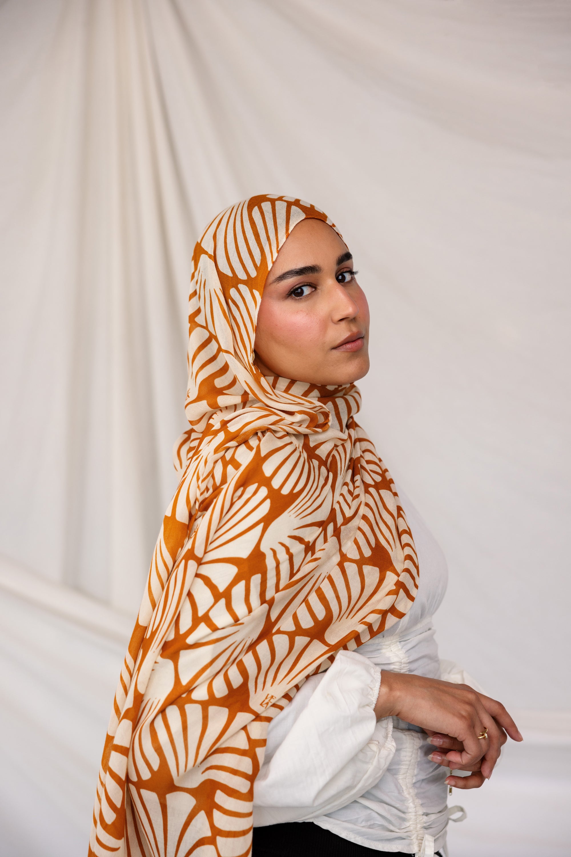 Woman wearing Amber Shells printed hijab against a plain background
