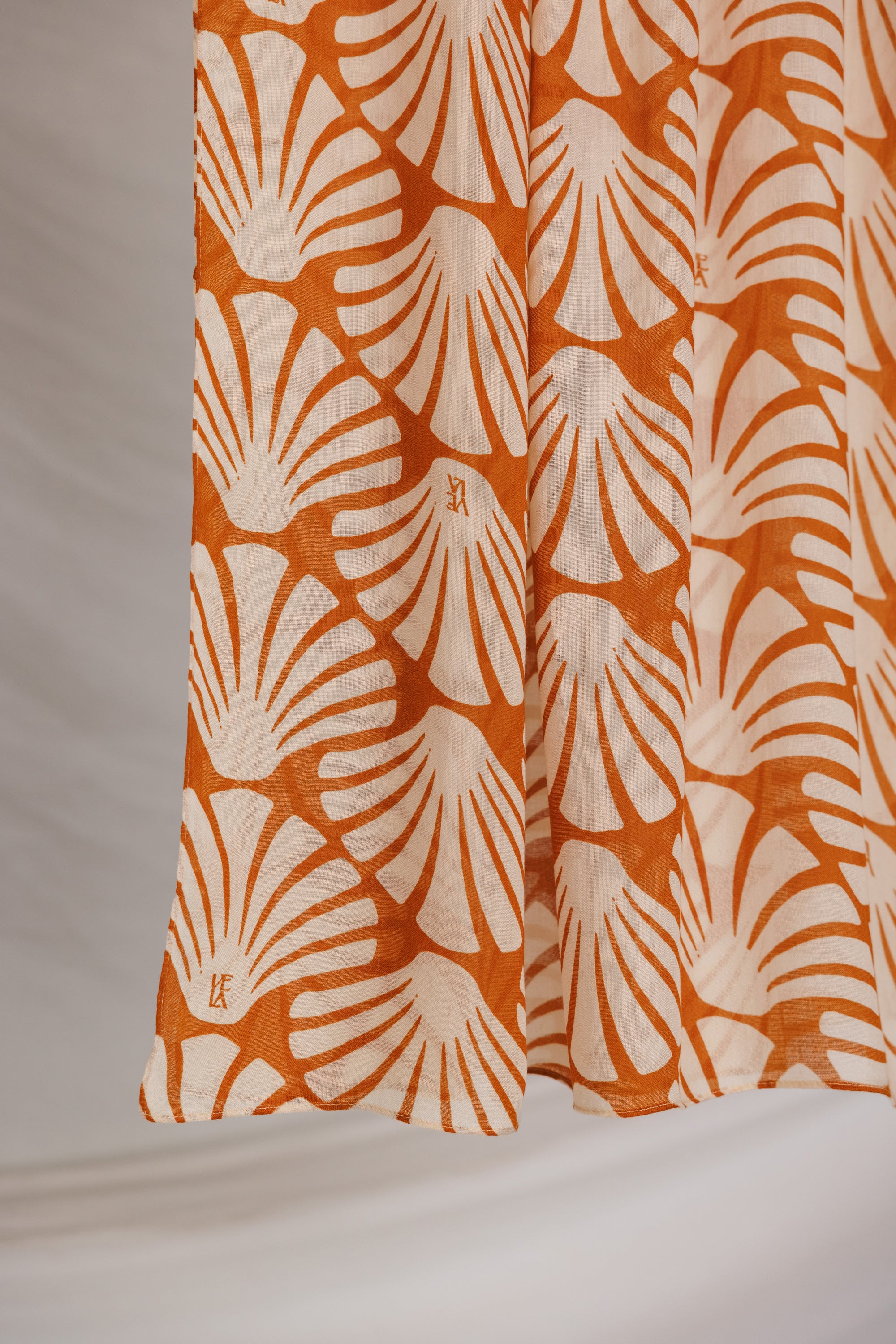 Fabric with orange shell pattern against a plain background