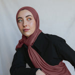 Model wearing burnt clay hijab against backdrop.