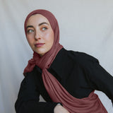 Model wearing burnt clay hijab against backdrop.
