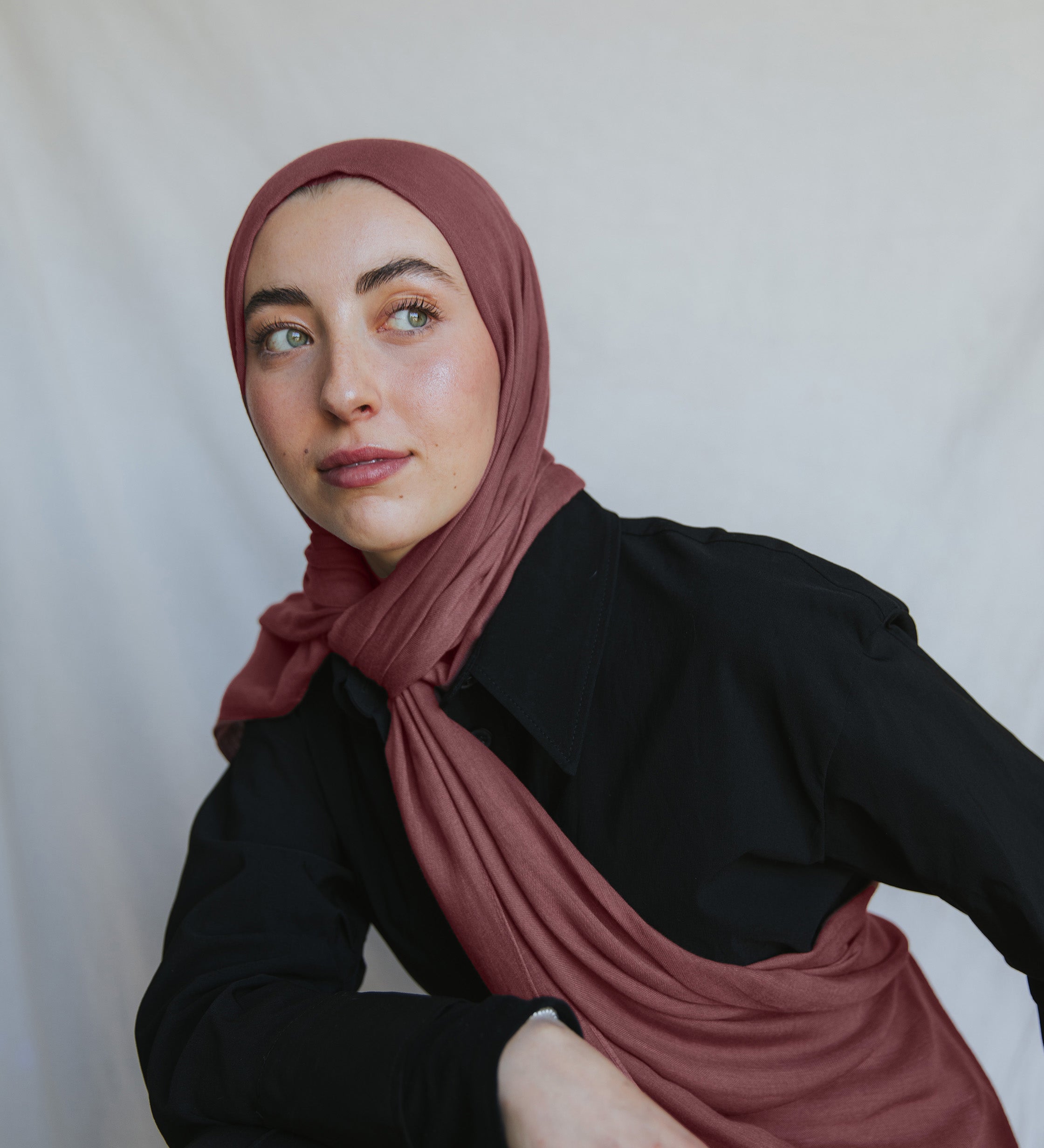 Model wearing burnt clay hijab against backdrop.