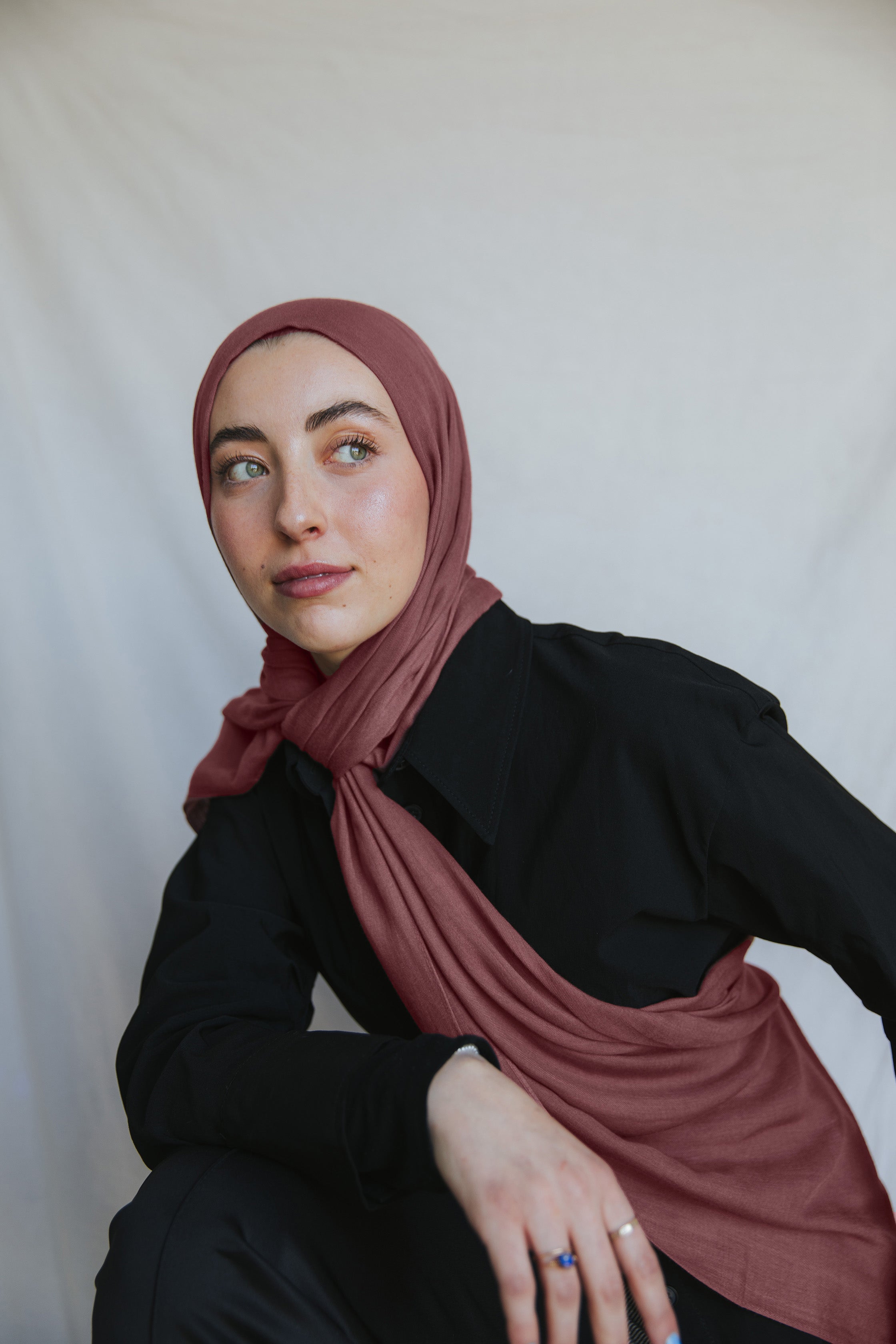 Model wearing burnt clay hijab against backdrop.