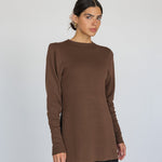 Woman wearing a brown long-sleeve top against a white background