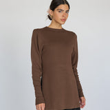 Woman wearing a brown long-sleeve top against a white background