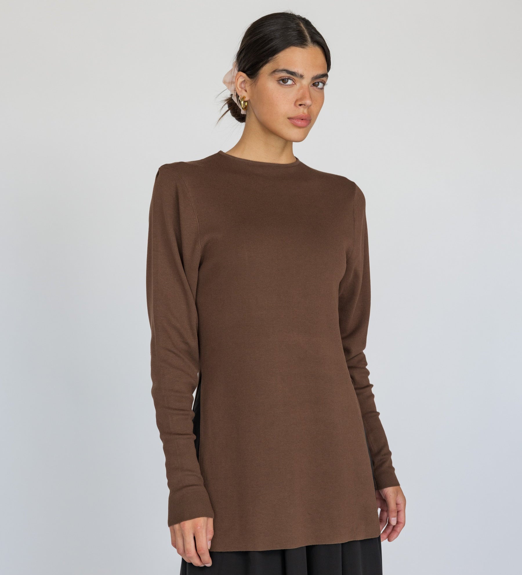 Woman wearing a brown long-sleeve top against a white background