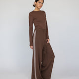 Woman wearing a brown long-sleeve top and wide-leg pants with a white background