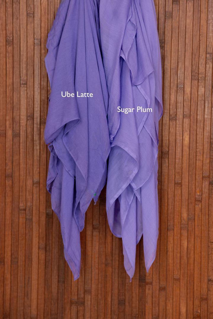 Color comparison shot of two purple hijabs draped over a wooden surface with 'Ube Latte' and 'Sugar Plum' labels.