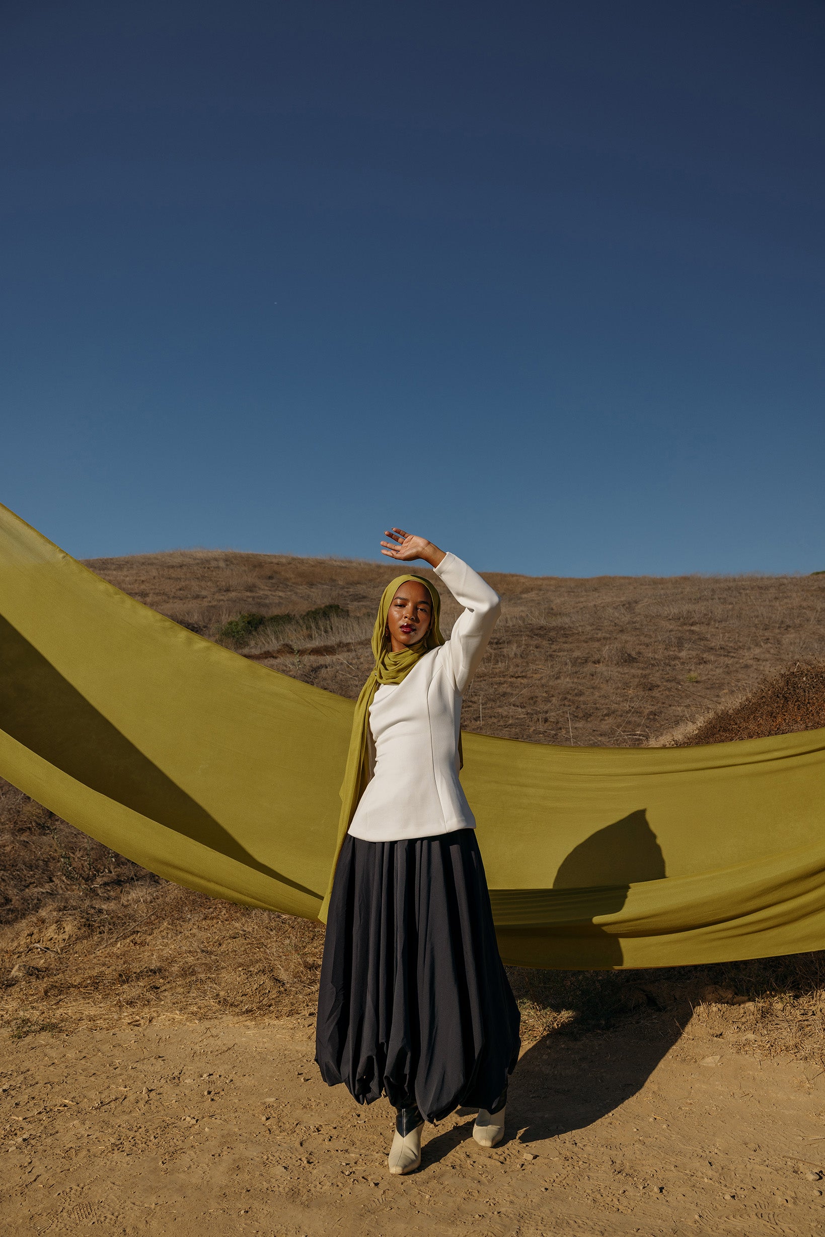 Model wearing Guava Green hijab standing in field.