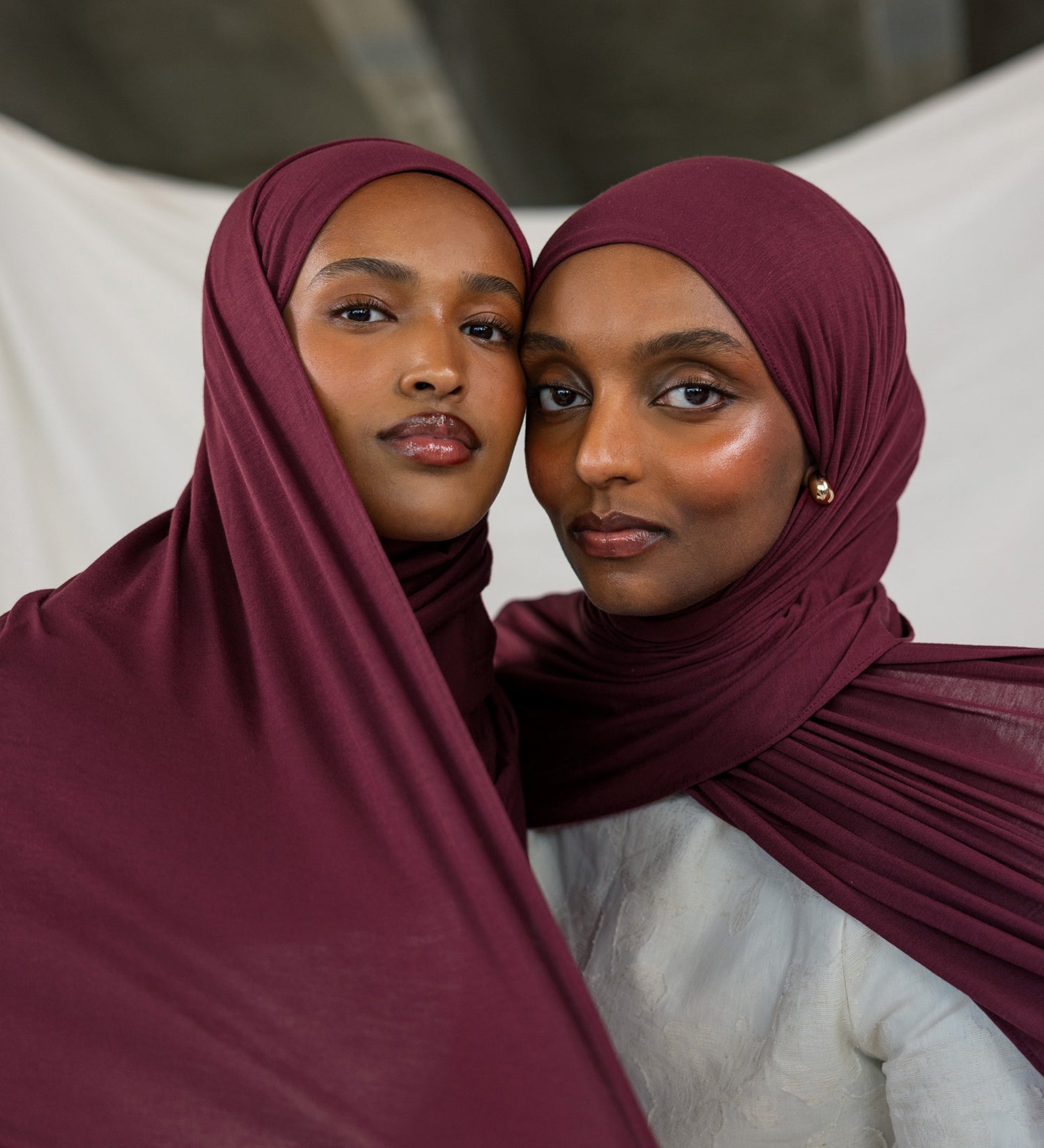 Two models side by side wearing Antique Cherry Jersey Lite, contrasting its tone shifting burgundy shade under different light.