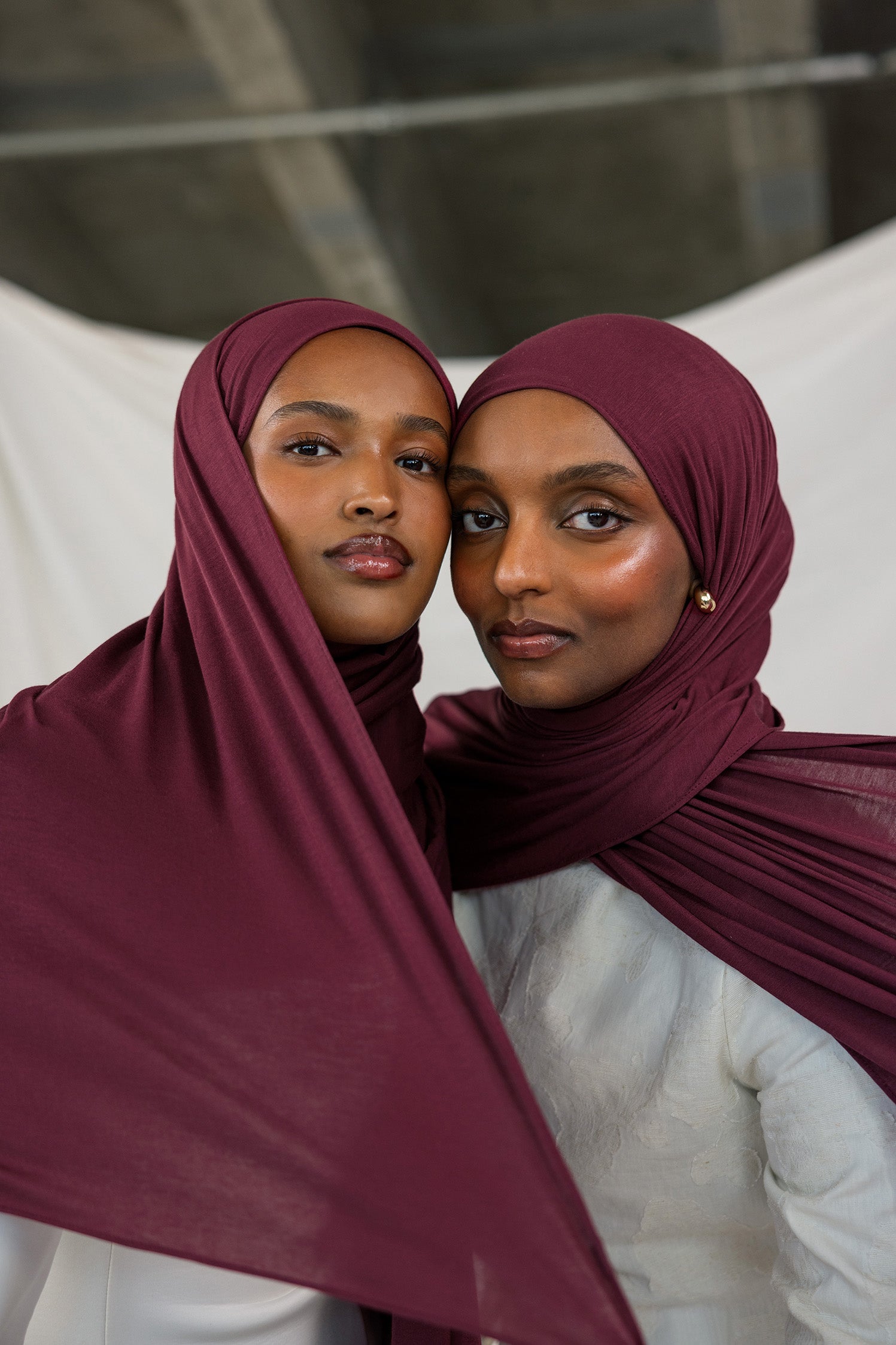 Two models side by side wearing Antique Cherry Jersey Lite, contrasting its tone shifting burgundy shade under different light.