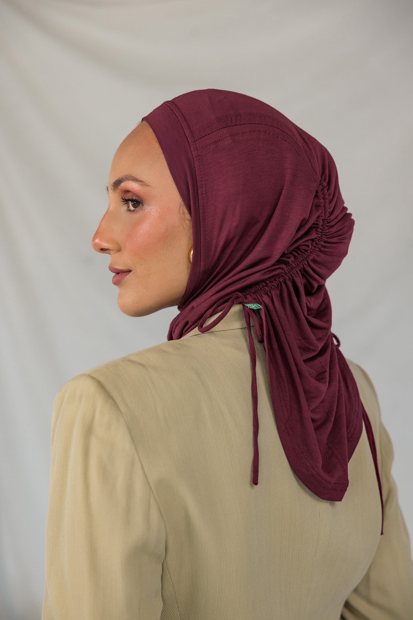 Model wearing a maroon ruched hijab against a plain background.
