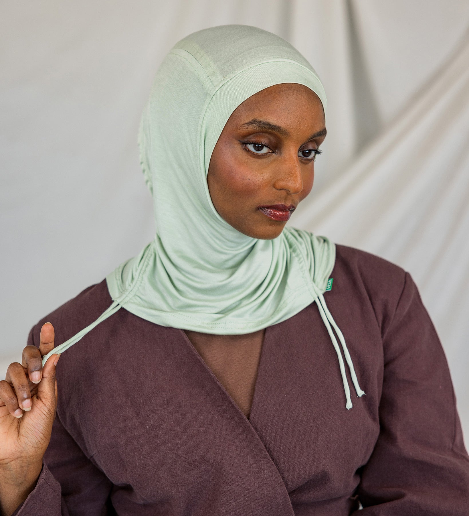 Model wearing Sage Mist Ruching Lite with light ruching around the face, emphasizing airy drape.