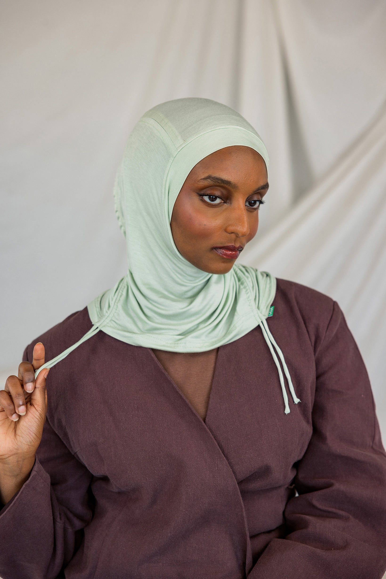 Model wearing Sage Mist Ruching Lite with light ruching around the face, emphasizing airy drape.