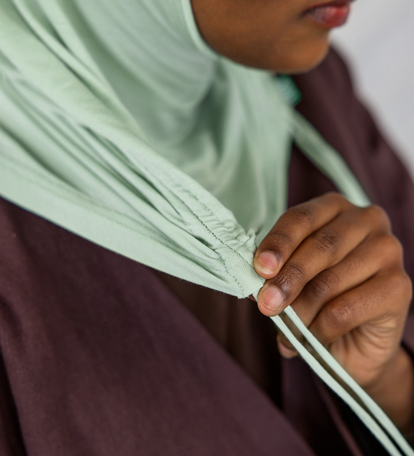 Close-up view of the Sage Mist Ruching Lite hijab depicting the model using the ruching strings.