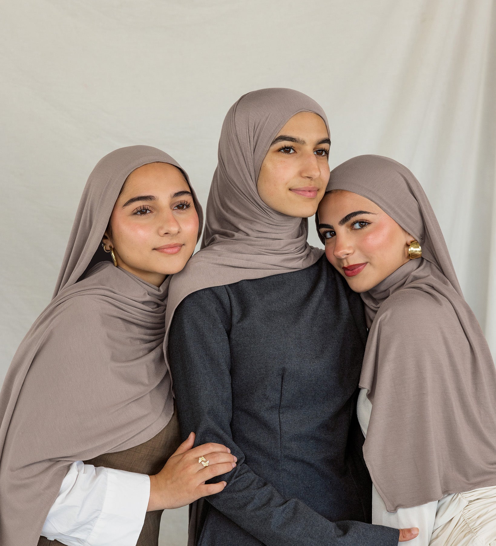 Three models stand together wearing Truffle Mink Jersey Lite, a universal taupe shade.