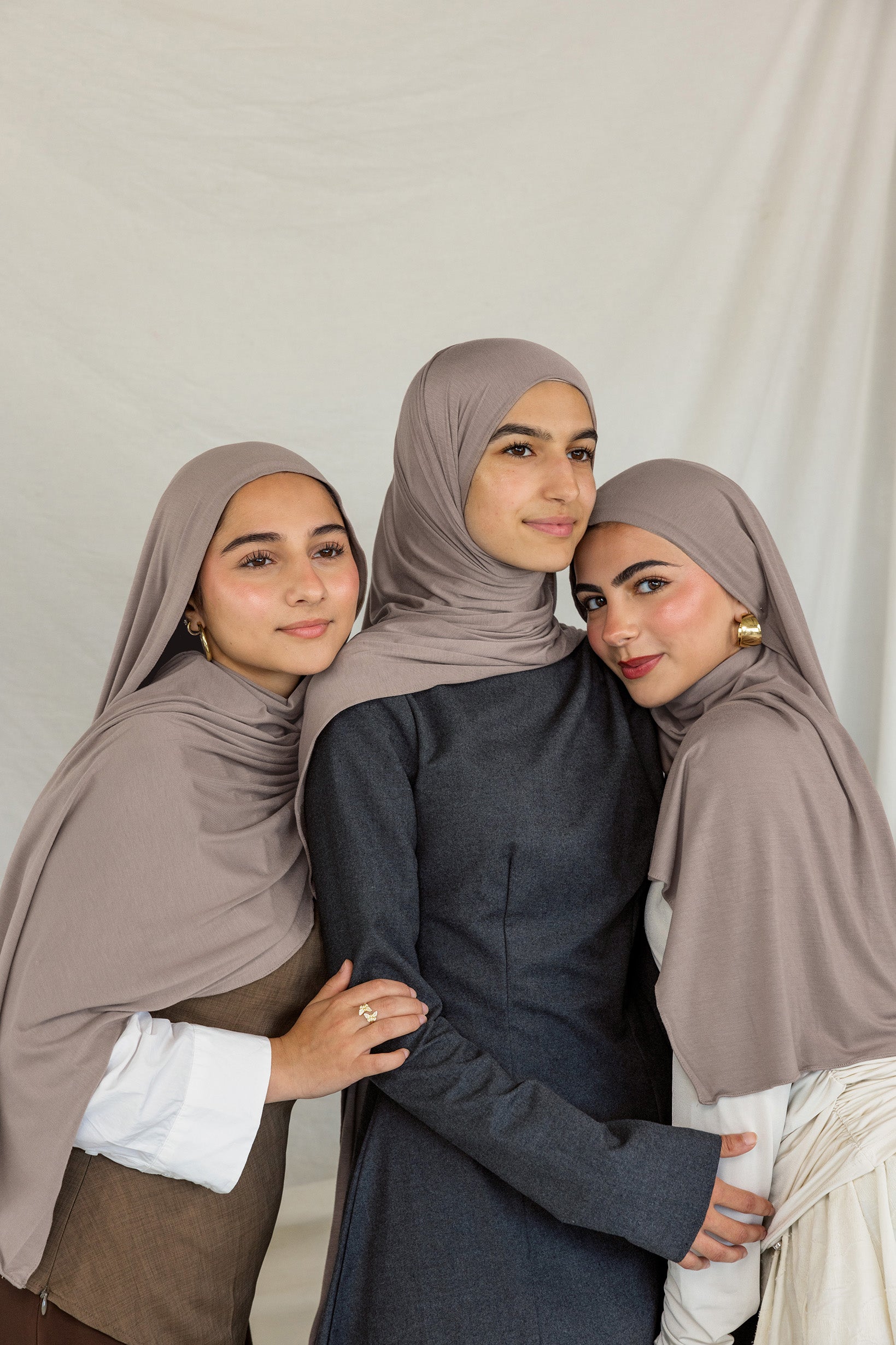Three models stand together wearing Truffle Mink Jersey Lite, a universal taupe shade.