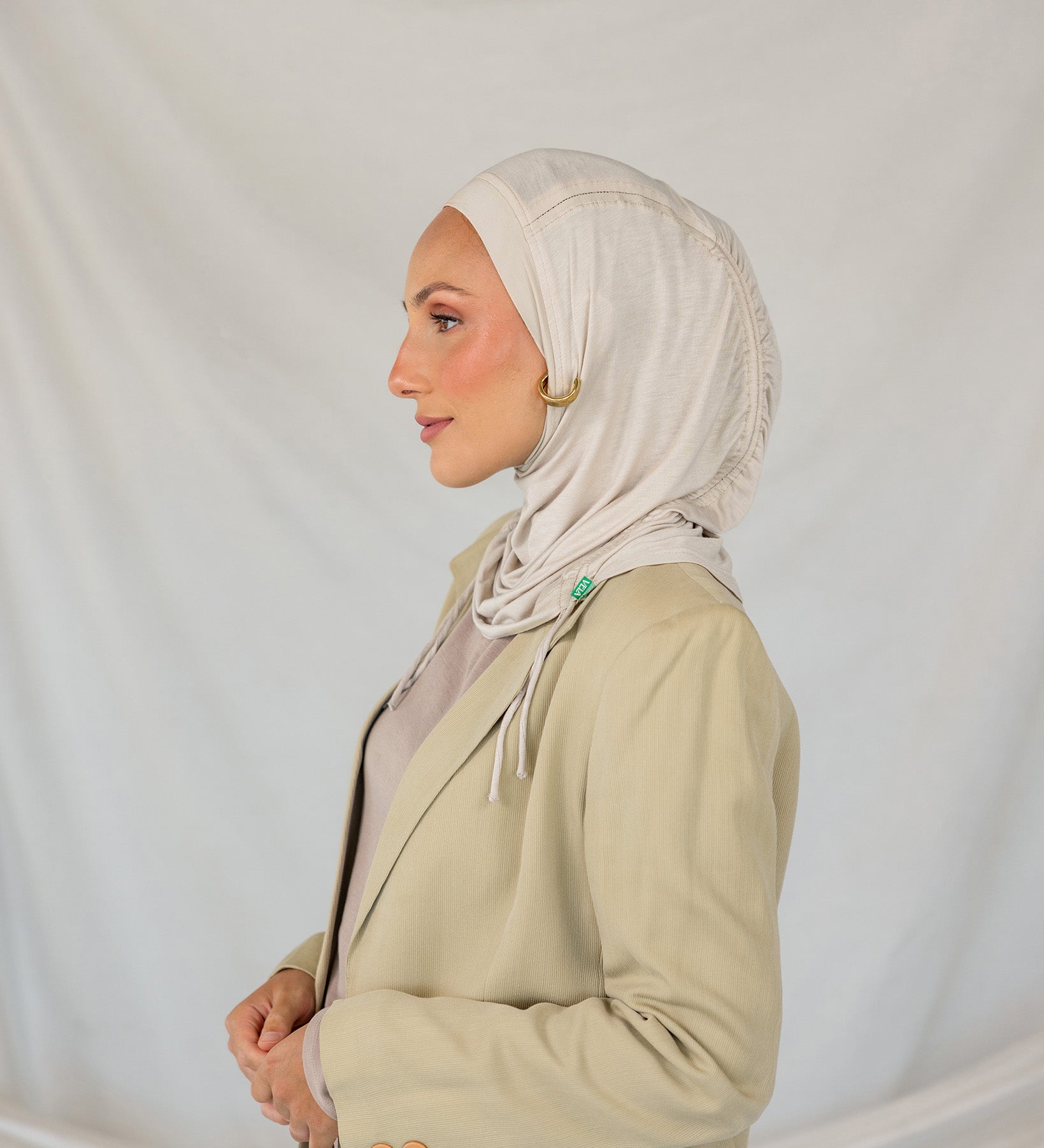 Model wearing Ashwood Ruching Lite fabric draped against white backdrop, revealing beige-ash tone and ruched design.