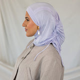 Woman wearing a lavender ruching hijab and beige suit against a plain background.