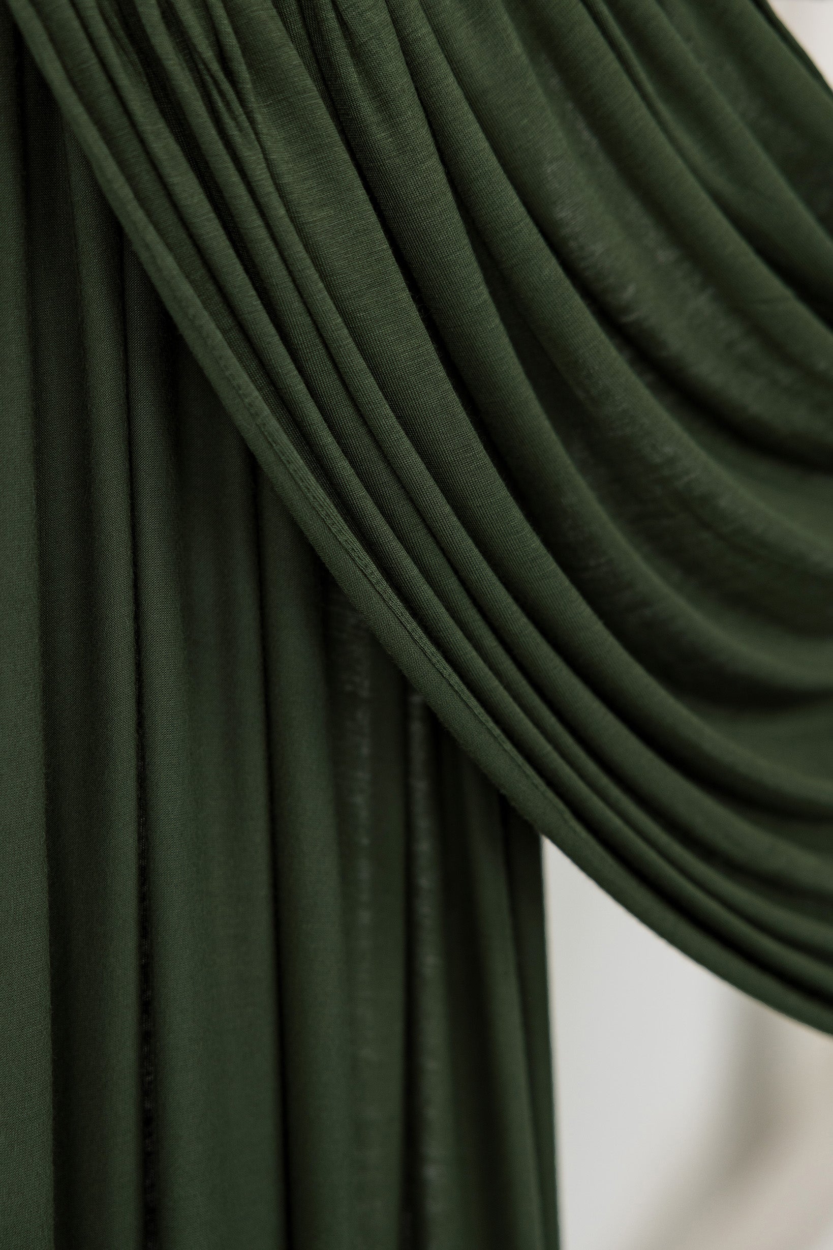 Close-up of Hunter Green Jersey Lite fabric draped smoothly against a white backdrop, showing its deep forest green tone and soft, lightweight texture.
