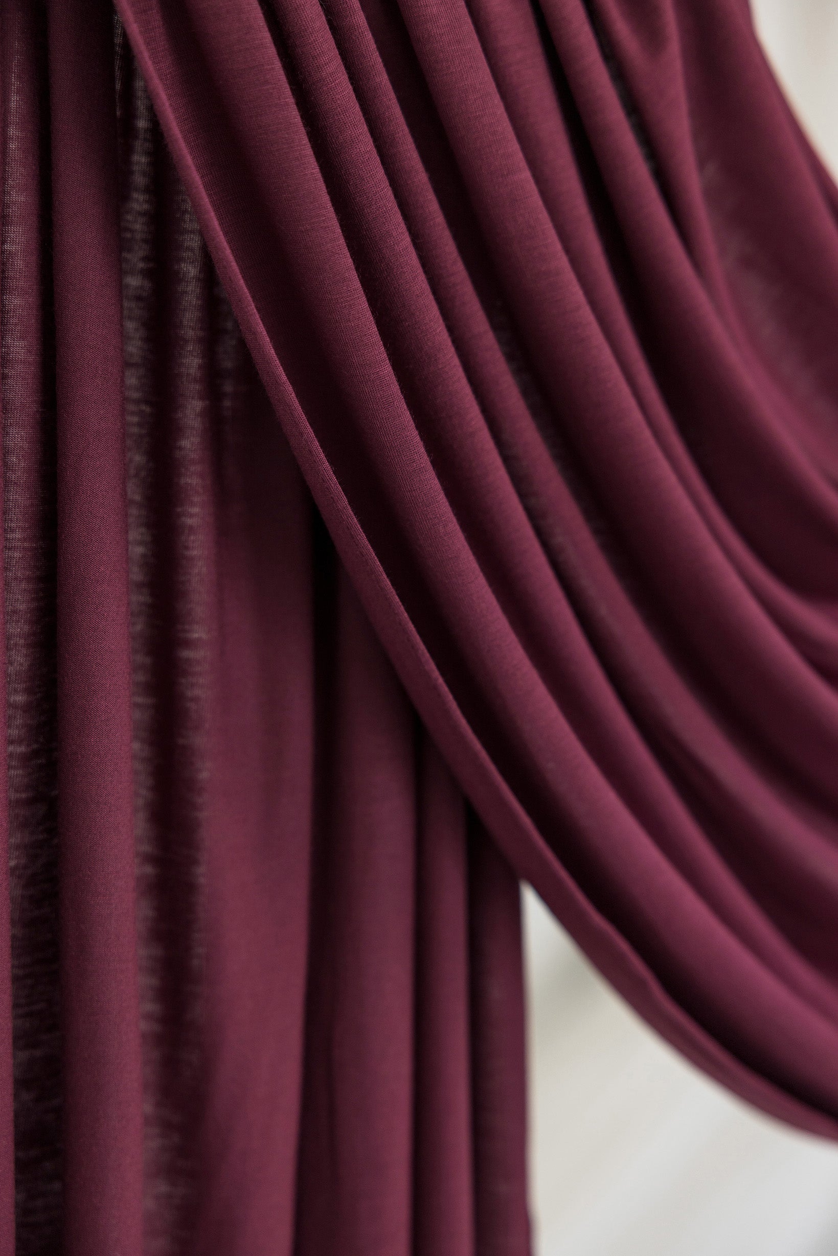 Antique Cherry Jersey Lite fabric swatch draped against white backdrop, showing rich deep maroon color and smooth, breathable jersey texture.
