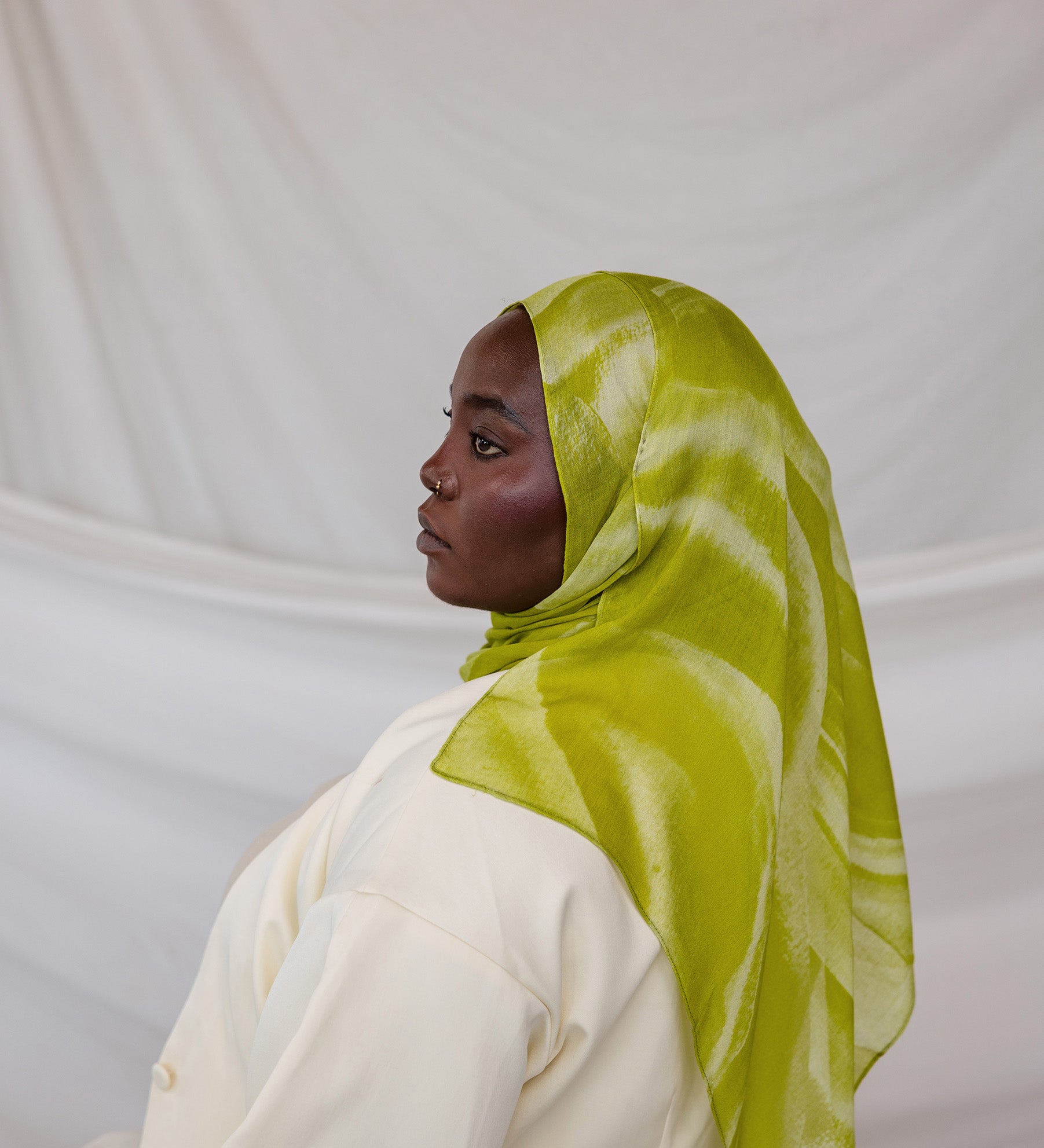 Person wearing a lime green sediment printed hijab against a white background