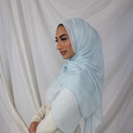 This is a lightweight woven hijab draped beautifully on a model showing the color  Fuji Blue is a serene, sky-inspired blue, named after the majestic Mount Fuji