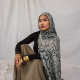Model shown sitting down and posing in Ink Cobra, a grey-toned snakeskin print scarf by VELA.