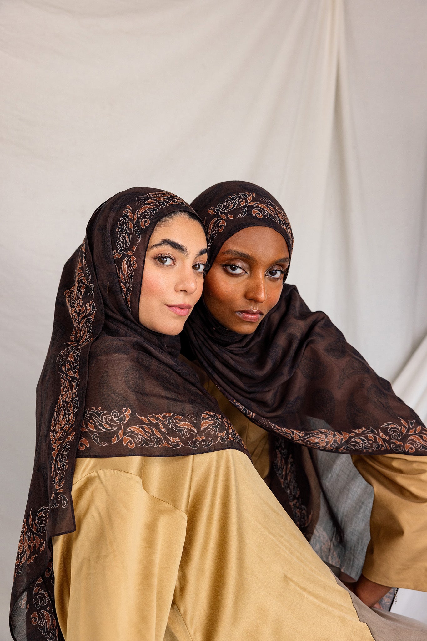 Two women posing in Chocolate Paisley hijabs, styled differently.