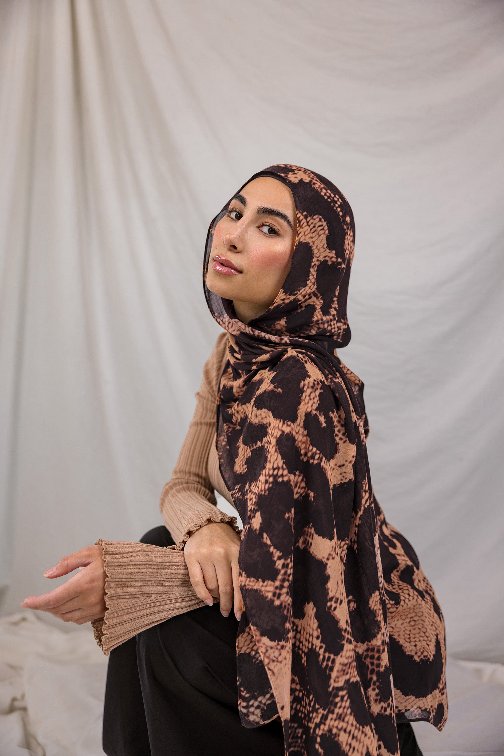 Model wearing a peach and tan based scarf with dark brown spots, called the Wild Savanna print.