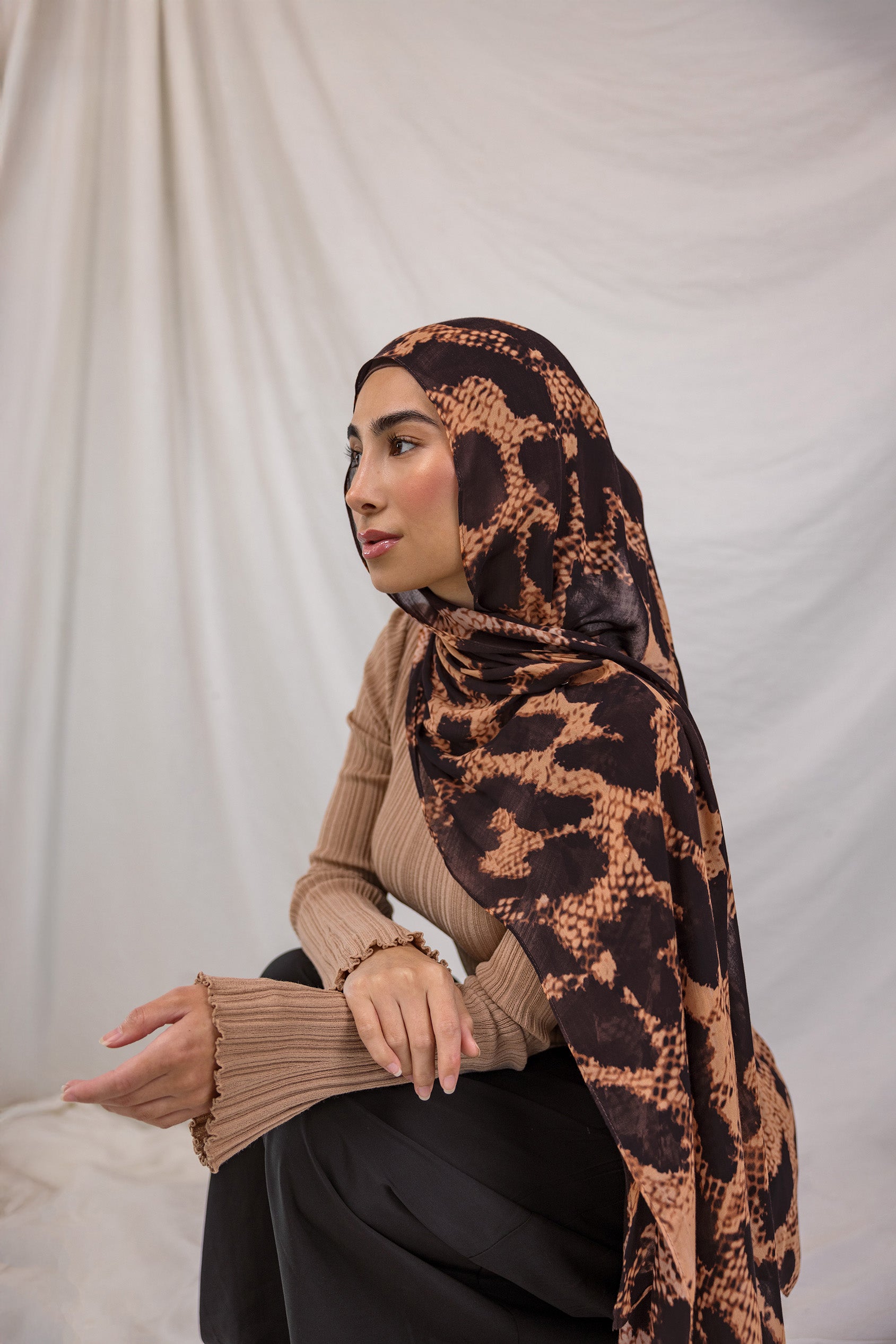 Model shown wearing Wild Savanna, a scarf from VELA that features a peach/orange/tan base that mimics and animal print, and dark brown spots.