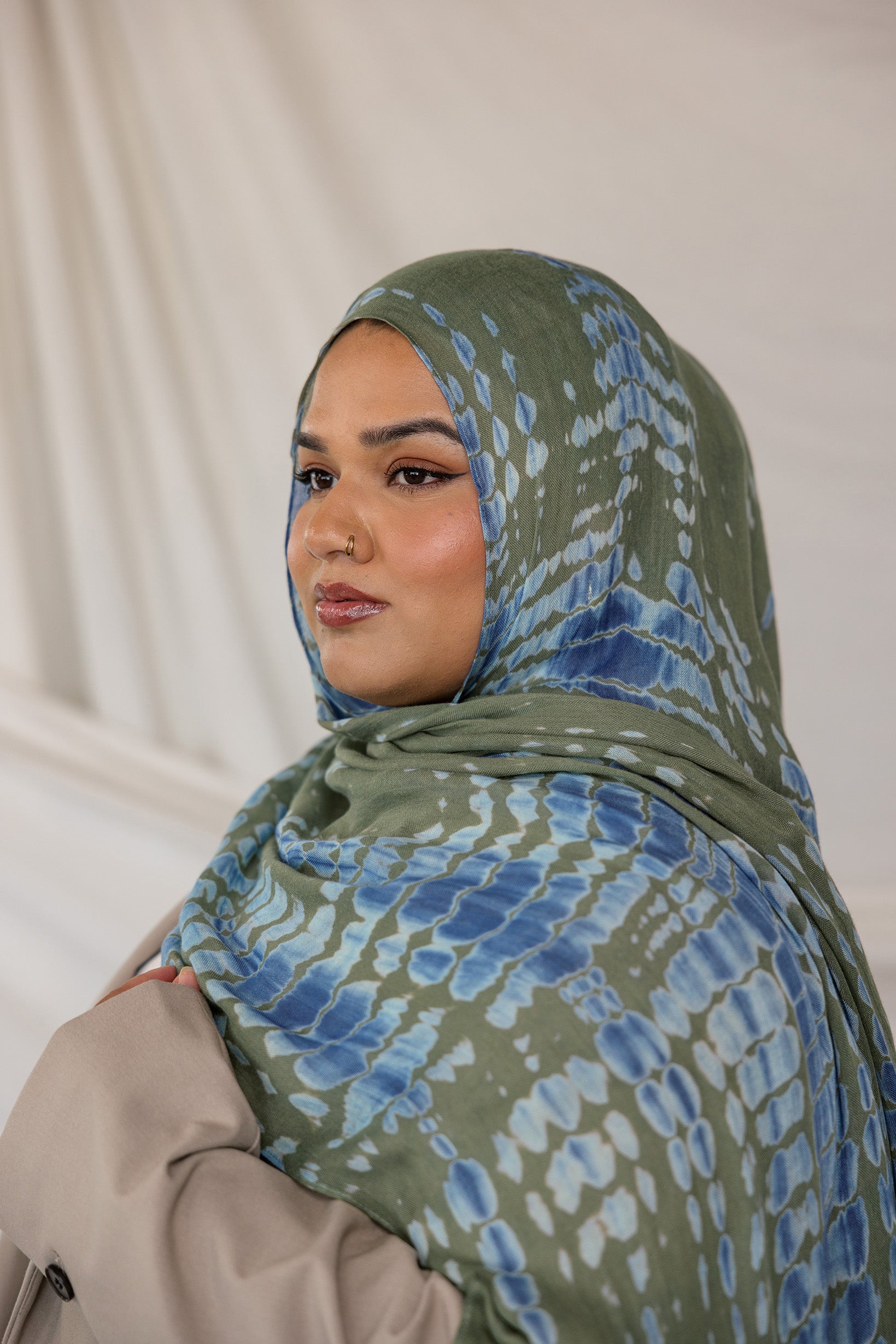 Woman wearing a green and blue Mermaid Ripple patterned hijab against a plain background