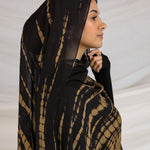 A woman wearing a black and yellow tie-dye patterned hijab.