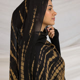 A woman wearing a black and yellow tie-dye patterned hijab.