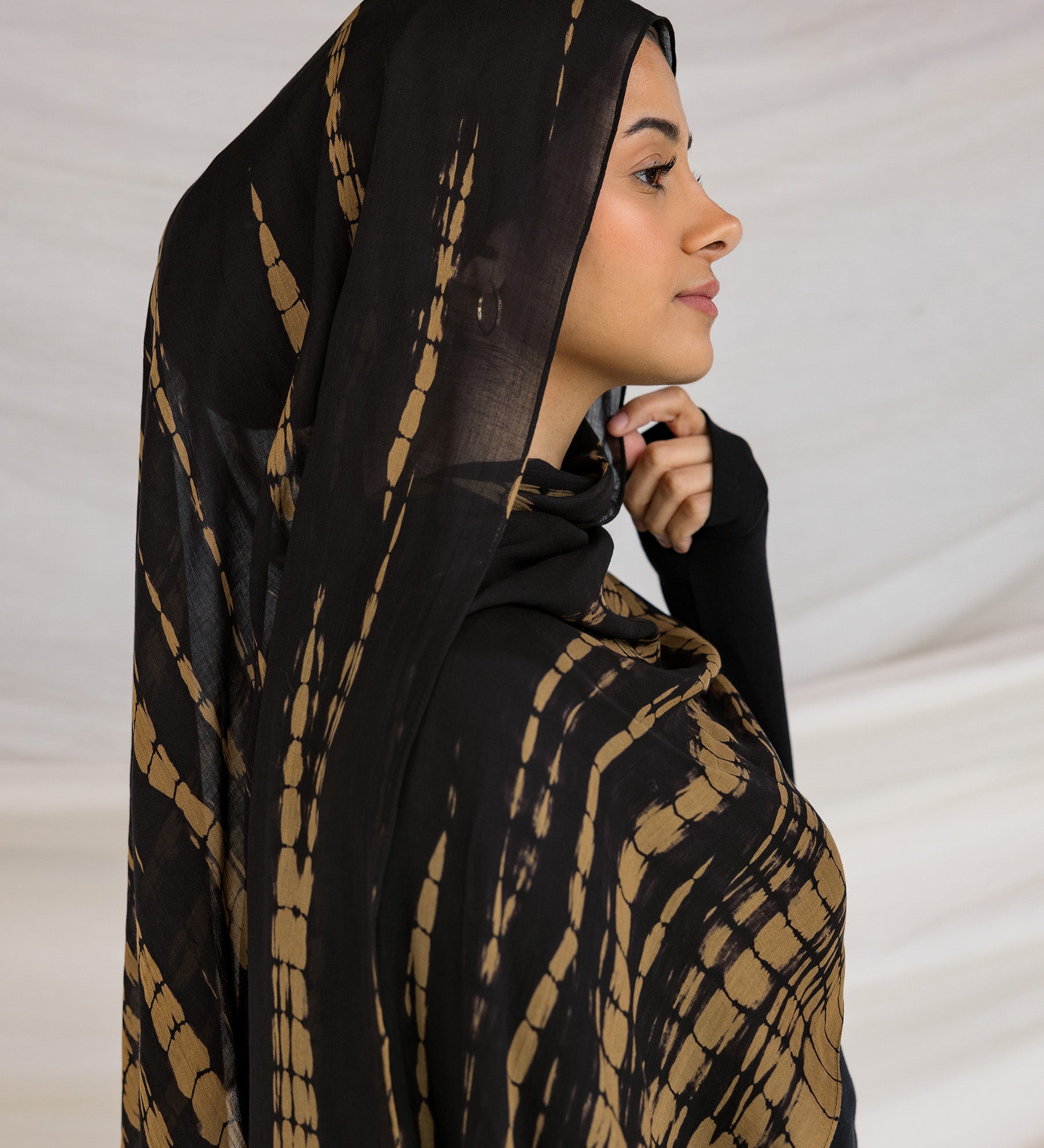 A woman wearing a black and yellow tie-dye patterned hijab.