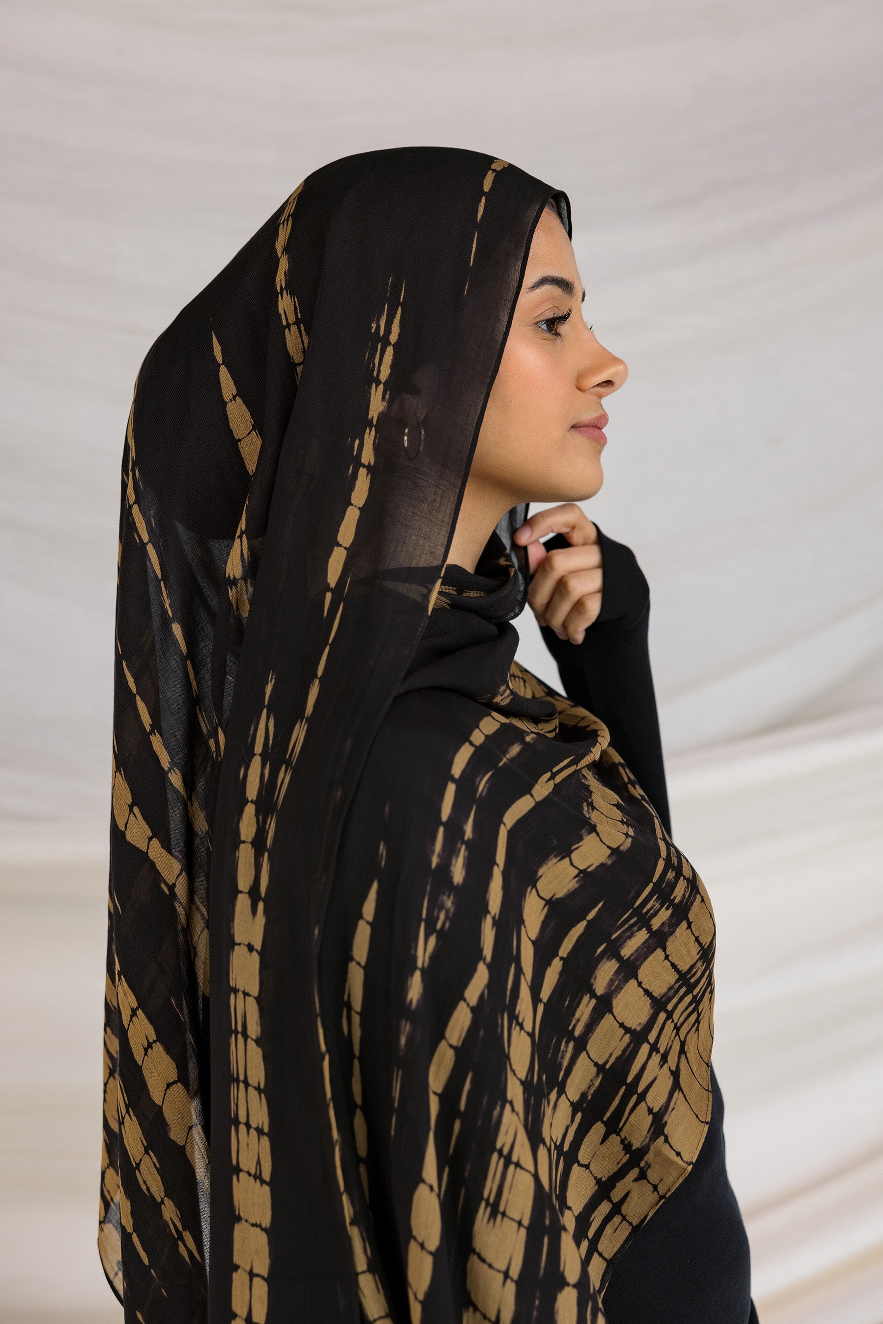 A woman wearing a black and yellow tie-dye patterned hijab.