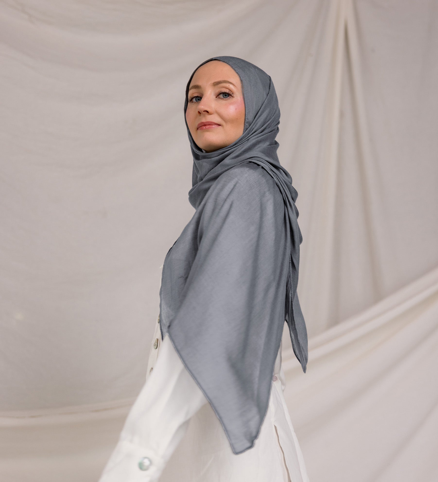 Model wearing the hijab, showing how the dark sage fabric wraps smoothly around the head and neck.