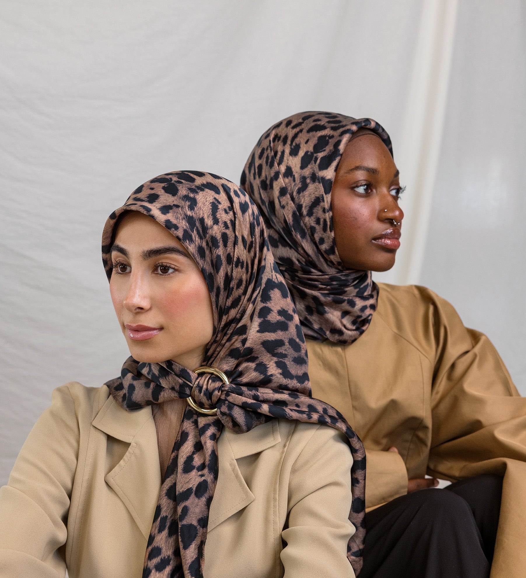 Two models styled in a silk hijab featuring a leopard print.