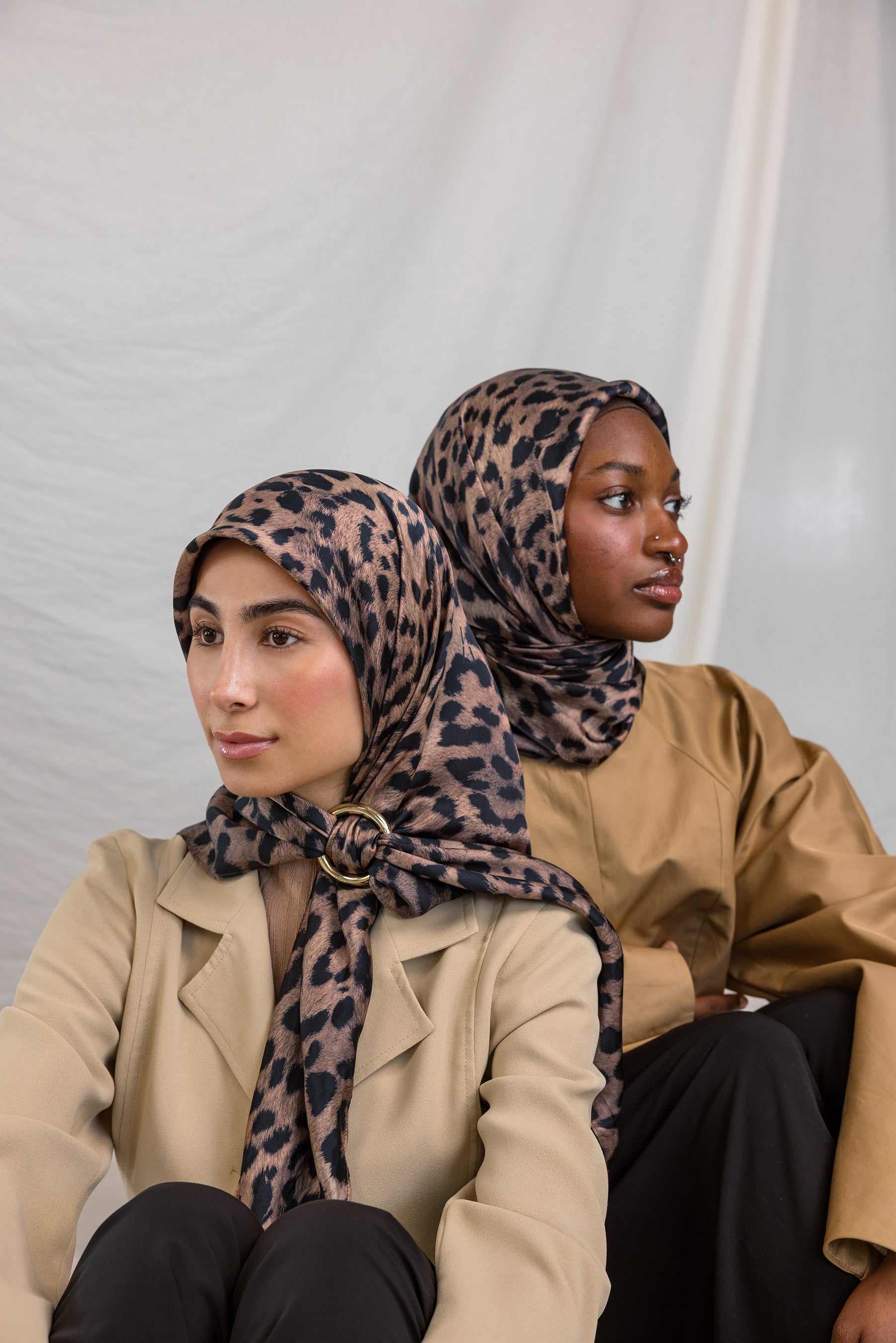 Two models styled in a silk hijab featuring a leopard print.